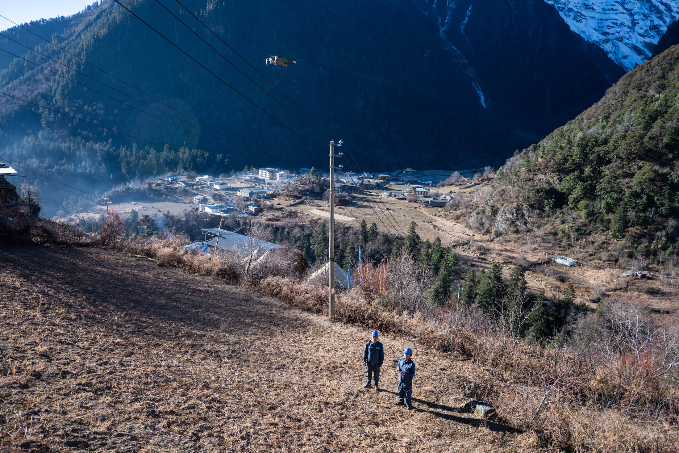 Wangden and his colleague use a drone to inspect power transmission lines in Deqen County, Yunnan Province